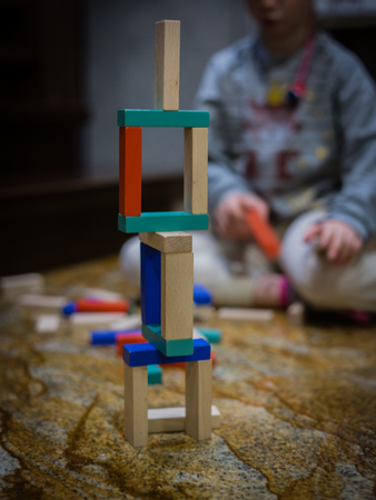A girl siting at background and a wood game on the floor. Some bricks out of focusの写真素材
