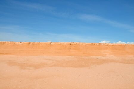 mound of orange sand and dry grass, blue sky with clouds, summer sunny day
の写真素材