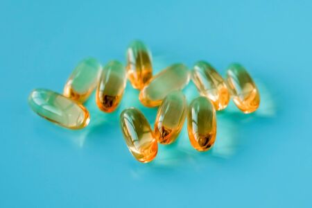 handful of omega 3 capsules on a blue background