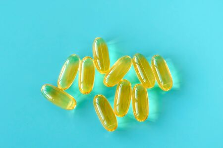 handful of omega 3 capsules on a blue background