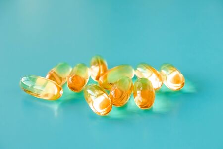 handful of omega 3 capsules on a blue background