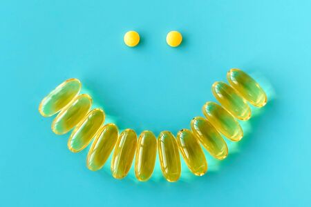 Smile from omega 3 capsules on  blue background, positive from pills, the concept of good mood and...