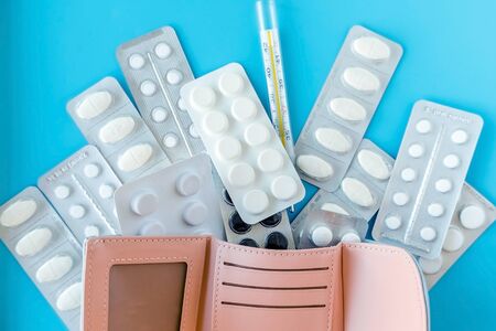 Empty wallet with white tablets of pills on 
blue backgroundの写真素材