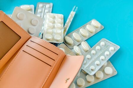 Empty wallet with white tablets of pills on blue background