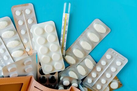 Empty wallet with white tablets of pills on blue background