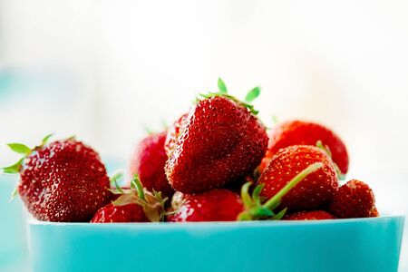 red juicy ripe strawberries in a blue vase on a light background. Healthy spring breakfast, fruit...