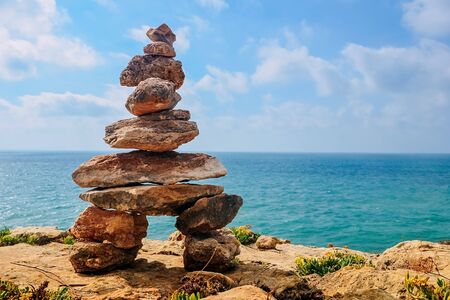 stone tower on a rock by the sea. sky with clouds, the concept of harmony, energy of life and...