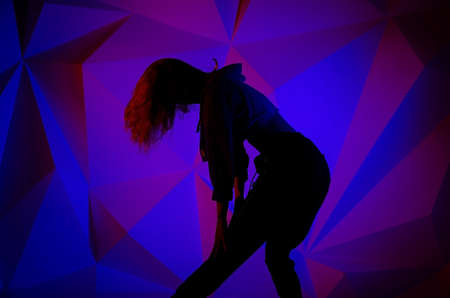 Woman dancing on the background of a beautiful multicolored wall. Sexy slim lonely girl with long...