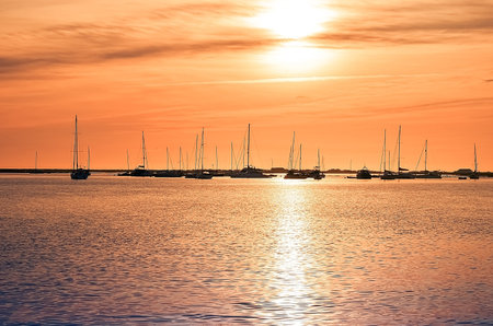 Beautiful sky in the bay in the city of Faro in Portugal. Silhouettes of yachts and boats at sunset near the waterの写真素材