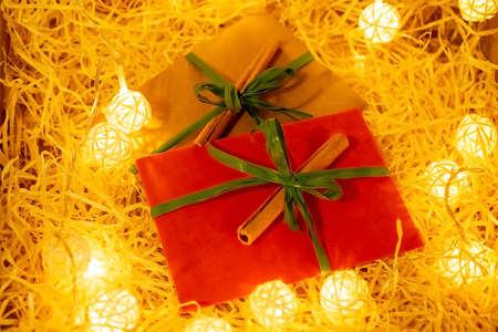 two envelopes with cinnamon on dry sawdust among balls from a garland. New Year's wrapping with green ribbon gift and letters.の写真素材