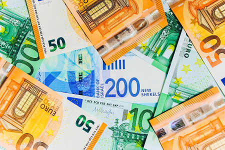 Two new bills of 200 shekels are on the background of 100 Euro. Cash background of black and white Euro bills, top view.の写真素材