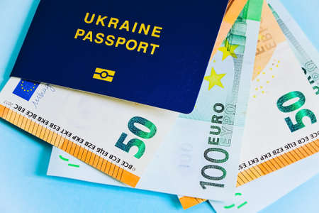 The Ukrainian biometric passport is on paper euro bills and dollars. Concept: increase of salaries, Ukrainians go abroad to work in Europe, Immigration to work, vacation abroad, visa for Europe.の写真素材