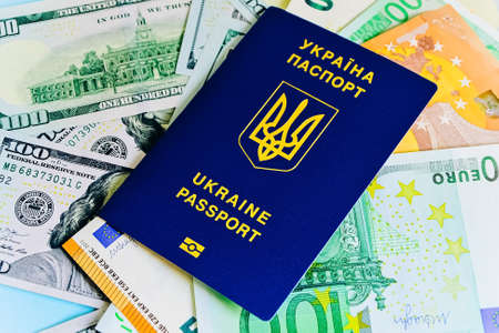 The Ukrainian biometric passport is on paper euro bills and dollars. Concept: increase of salaries, Ukrainians go abroad to work in Europe, Immigration to work, vacation abroad, visa for Europe.の写真素材