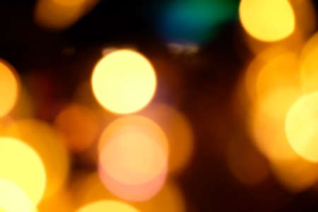 Blurred Christmas background, abstraction. orange and yellow glare garlands on a black background.の写真素材