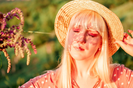beautiful girl in a pink dress and a straw hat on a picnic in a spring park. woman holding a bouquet of lavenderの写真素材