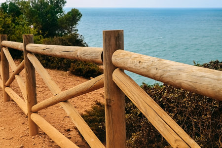 Wooden fence on the coast of Benagil beach in Portugal. View of the Atlantic Ocean on a clear day