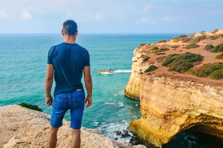 one slender guy is standing on a rock in Portugal. back view of the oceanの写真素材