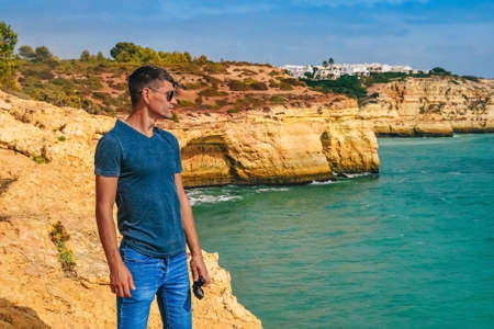one slender guy is standing on a rock in Portugal. guy looks into the distance, ocean viewの写真素材