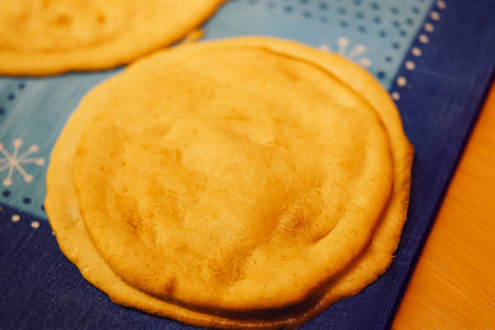 many fried pancakes with a golden crust lie on a blue towel, a traditional dish shrovetide