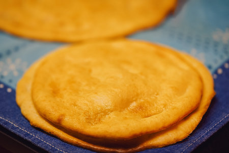 many fried pancakes with a golden crust lie on a blue towel, a traditional dish shrovetide