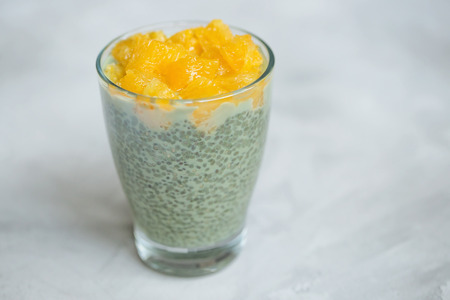 Matcha green tea chia seed pudding dessert with orange in a glass. Close up, top view, flat lay. Superfood and vegan food concept. Gray background, copy space.の写真素材