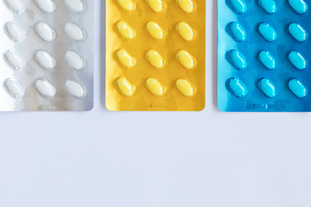 Set of various tablets in a blue, yellow and white pack blister pack. Healthcare and medical concept. Copy space, white background.の写真素材