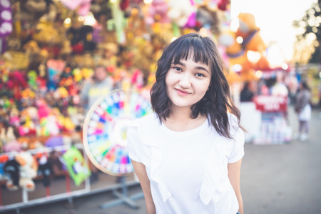 Beautiful asian girl in an amusement park, smiling. Copy space.