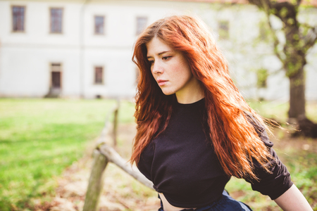 Beautiful redhead young woman deep in her thought. Outdoor portrait.の写真素材