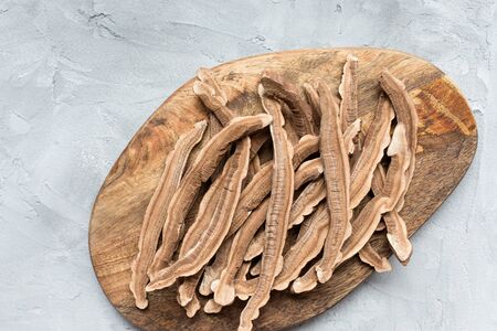 Slices of dried lingzhi mushroom, also called reishi or Ganoderma Lucidum, on a wooden board, gray background. Chinese traditional medicine product. Copy space.の写真素材