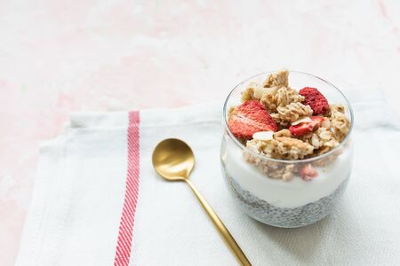 Overnight chia seed parfait pudding with almond milk, yogurt, homemade granola, dried strawberries and almonds in a glass. Superfood and vegan food concept. Copy space, selective focus.の写真素材