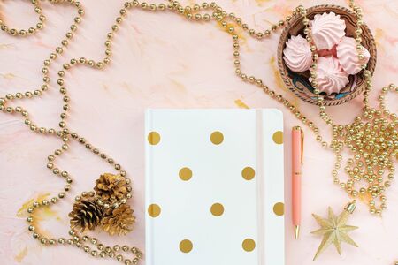 Notepad, pen and christmas decoration on a desk workspace, pink backround. Flat lay, top view, social media hero header template. Winter holidays to do list concept.の写真素材