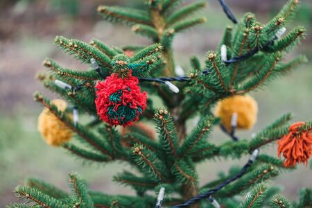 Wool handmade decoration on a Christmas tree outdoor. Diy yarn crafts creative ideas for children. Environment, recycle and zero waste concept. Selective focus.の写真素材