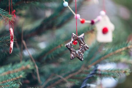 Handmade clay decoration on a Christmas tree outdoor. Diy creative ideas for children. Environment concept. Selective focus, copy space.の写真素材