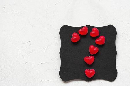 Question mark made of jelly hearts on a black board, white background, copy space. Top view, flat lay, mockup. Valentines Day conceptの写真素材