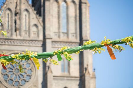 Outdoor Easter decorations on streets of Prague, rose window of St Ludmila Church in background,...