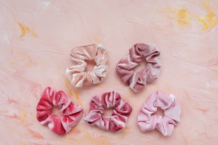 Collection of trendy velvet scrunchies on pink background. Diy accessories and hairstyles concept,...