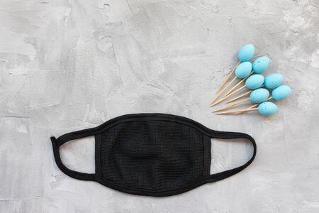 Easter during coronavirus concept. Easter sticks for appetizers with eggs and mask on gray...