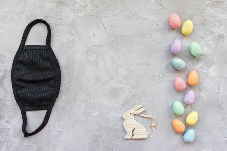 Easter during coronavirus concept. Eggs, bunny and mask on gray. COVID-19 outbreak, celebration, work and stay home concept, copy spaceの写真素材