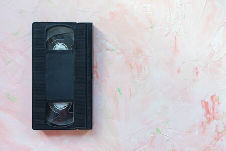 Black vintage VHS video tape on pink. Retro minimalist background, copy space