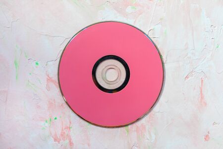 Red CD or DVD disc on pink. Retro minimalist background, copy space