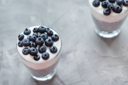 Chia seed pudding with almond milk, yogurt and blueberries dessert in a glass. Superfood and vegan food concept. Gray background. Copy space, selective focusの写真素材