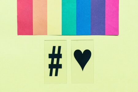 Rainbow flag, hashtag and heart symbols on yellow background.  love concept. Copy spaceの写真素材
