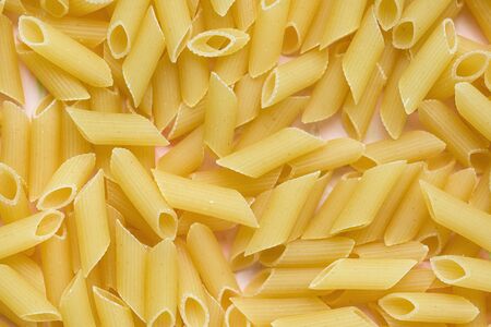 Raw traditional Italian penne pasta on pink background. Close upの写真素材