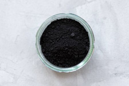 Black activated charcoal powder in a glass. Superfood, ingredient for cosmetics and vegan, vegetarian food, detox concept. Gray background. Copy space, selective focusの写真素材