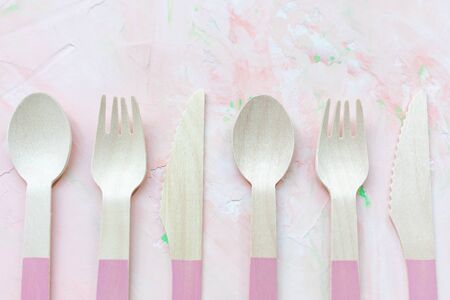 Disposable eco friendly wooden cutlery on pink background, many spoons, knives and forks cutlery. Zero waste concept, recycling. Plastic-free alternative for environmental protection. Copy spaceの写真素材