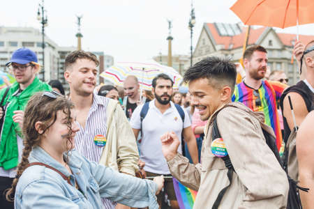 Prague, Czech Republic - August 10, 2019: Participants of Prague Gay Pride parade. Young couple or friends, girl and boy dancing in a crowd under the rain. Happy people with umbrellasのeditorial素材