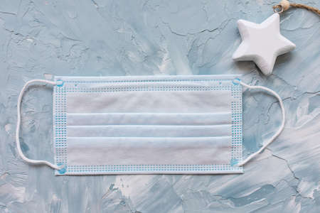Blue surgical mouth mask and white christmas star. Quarantine, lockdown and coronavirus Covid-19,...
