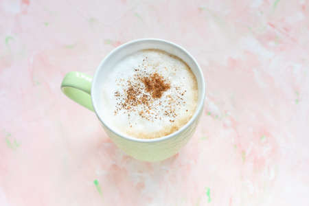 Cup of latte coffee on light pink background