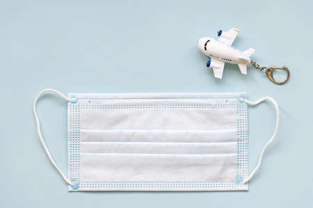 White surgical face mask and airplane on blue