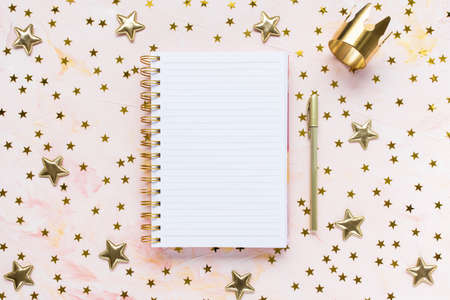 Notepad, pen, gold crown and stars decoration on woman desk workspace, pink background. Winter holidays holidays preparation and lifestyle concept. To Do List template. Flat lay, top view, copy spaceの写真素材